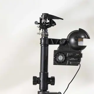 a black motion sprinkler mounted on a stand in the grass