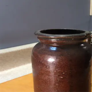 a brown ceramic fermentation crock on a wooden countertop