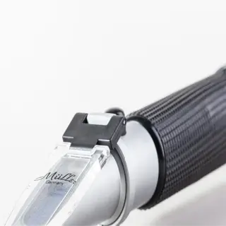 a close-up of a handheld brix refractometer with a black and silver design