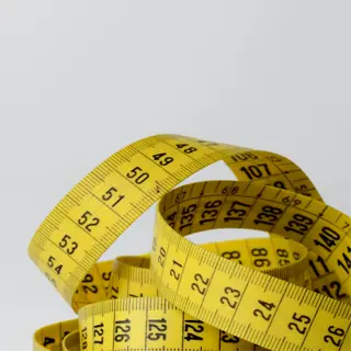 a coiled yellow measuring tape with centimeter markings, used for precise measurements in various activities