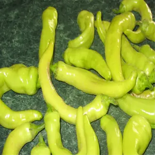 a collection of fresh, curved banana peppers with a vibrant yellow-green color, scattered on a dark surface