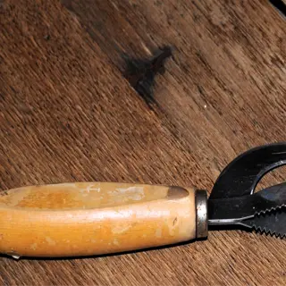 a garden knife with a wooden handle and a serrated blade on a wooden surface