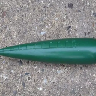 a green plastic seed dibber tool used for planting seeds at the correct depth