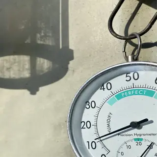 a hanging analog humidity gauge showing a reading of around 20%