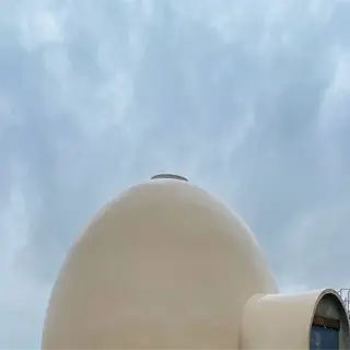 a large, beige humidity dome structure with a car parked nearby