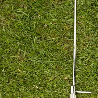 a metal soil probe resting on a bed of green grass