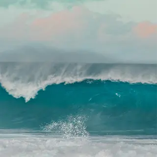 a powerful seascape with a towering turquoise wave crashing against the shore under a cloudy sky