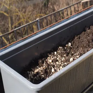 a rectangular self-watering box filled with soil on a balcony