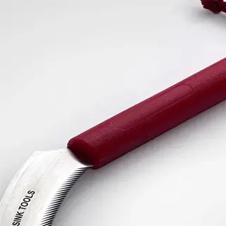 a red-handled sickle with 'neversink tools' inscription, a sharp harvesting tool for cutting