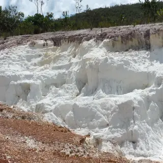 a rugged kaolin clay barrier contrasting with the red soil, under a partly cloudy sky