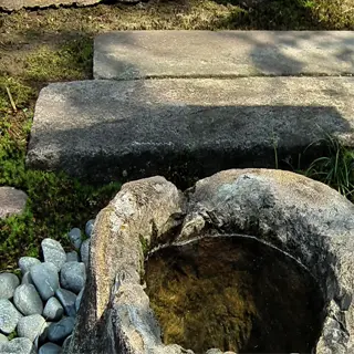 a rustic stone root washer filled with water, surrounded by pebbles