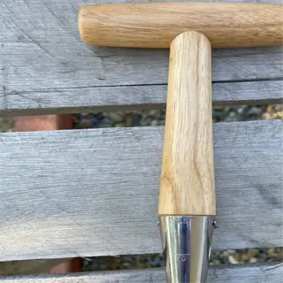a seed dibber with a wooden handle and metal tip, placed on a wooden surface