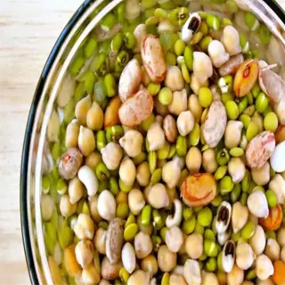 a seed soaking bowl filled with a variety of legumes including chickpeas and beans