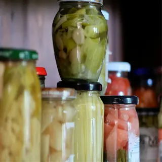 a shelf filled with various pickling jars containing pickled vegetables