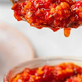 a spoonful of vibrant red garlic-chili sauce dripping with rich flavor