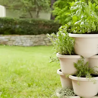 a stack of white stackable planters with various herbs in a garden