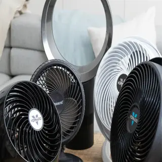 a variety of fans on a wooden table, including a large black fan in the foreground