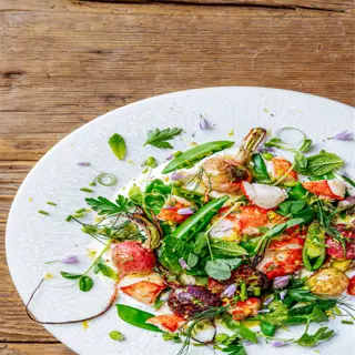 a vibrant spring pea salad with fresh vegetables, herbs, and a creamy dressing, presented on a white plate