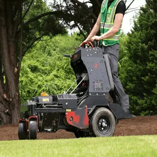 a worker operating a lawn aeration machine on grassy terrain with trees in the background