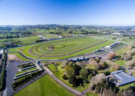 aerial view of pukekohe park raceway with multiple racing tracks, grandstands, and surrounding countryside under clear blue sky