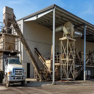 an industrial nut dehuller machine in a large shed with a conveyor system