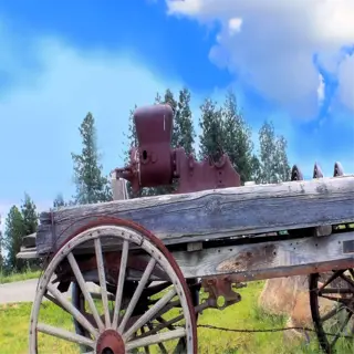 an old wooden wheeled cart with rusty wheels in a grassy field
