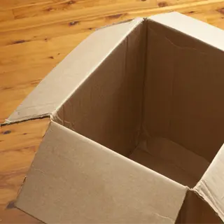 an open, empty cardboard box on a wooden floor