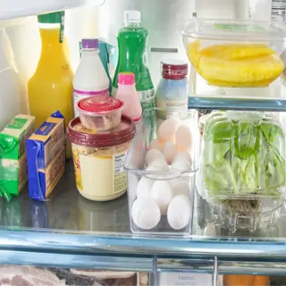 an open refrigerator with a crisper drawer containing fruits and vegetables