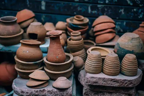 assortment of different sized terracotta pots and planters displayed on stacked stone surfaces against a textured blue background
