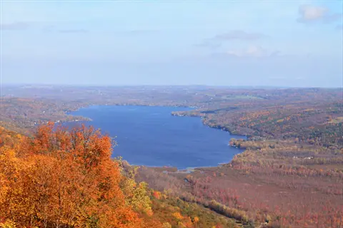 autumn foliage surrounds honeoye lake under a partly cloudy sky