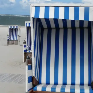 beach chair with striped canopy providing wind protection on sandy shore