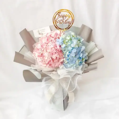 birthday bouquet featuring blue pink hydrangea flowers with 'happy birthday' topper and decorative wrapping