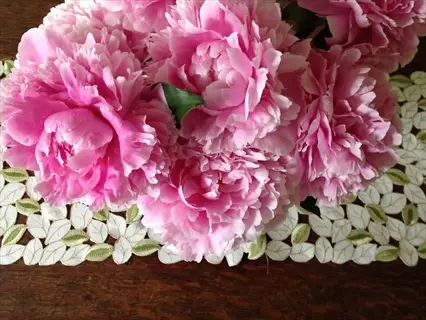 bouquet of sarah bernhardt peony flowers on decorative leaf-patterned placemat