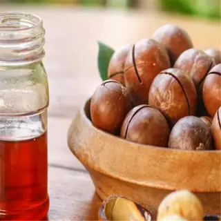 bowl of macadamia nuts with a jar of honey and a wooden spoon