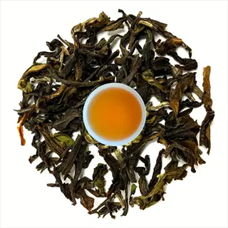 circular arrangement of dried oolong tea rolled leaves with central cup of brewed tea