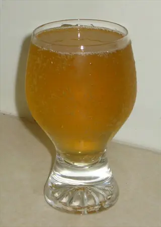 close-up of a chilled glass filled with golden ginger ale showing carbonation bubbles