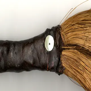 close-up of a traditional root brush with a dark handle and light-colored bristles