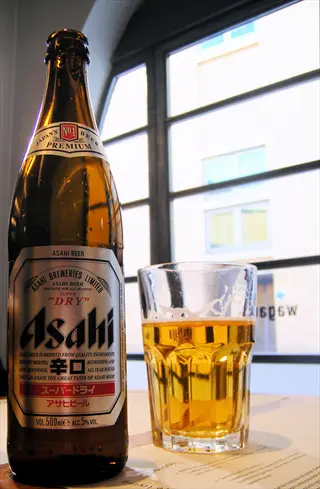 close-up of asahi beer bottle and glass on a table near a window