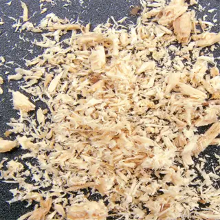 close-up of fine, light-colored sawdust on a dark surface