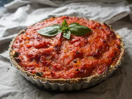 colorful tomato tart with a crumbly crust, vibrant red tomato topping, and fresh basil garnish in a metal pan