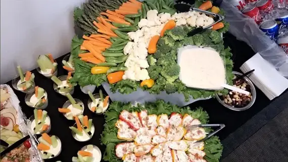 colorful vegetable buffet featuring celery sticks and cauliflower florets as companion plants, arranged with carrots, broccoli, stuffed peppers, and dips on a dark table