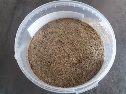 container of bone meal fertilizer showing granular texture with visible small bone fragments