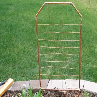 copper wire garden grid trellis in a mulched garden bed