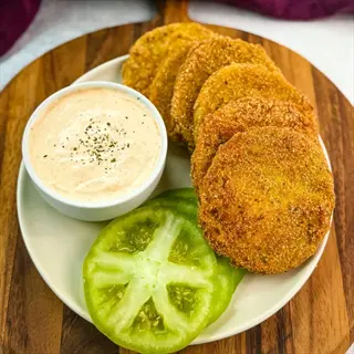 crispy fried green tomatoes with fresh slices and dipping sauce on wooden board