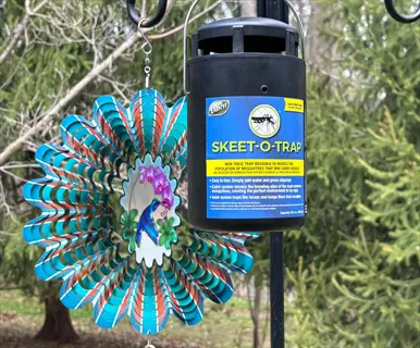 dalen skeet-o-trap ultraviolet insect trap hanging outdoors with decorative wind spinner, designed for mosquito control in garden settings