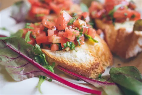 dark tomato bruschetta with fresh diced tomatoes, herbs, and greens on toasted bread slices