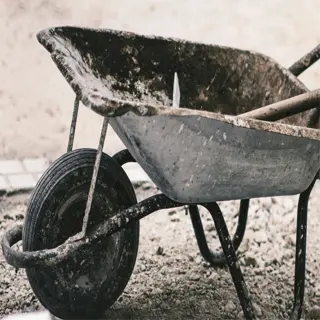 dirty gardening tools: a muddy wheelbarrow on a gravel surface