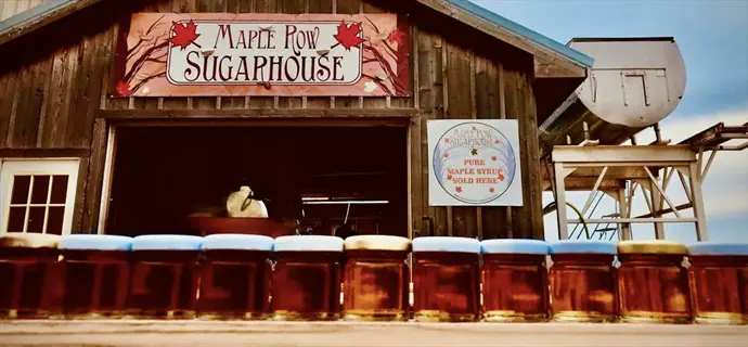 exterior of unity sugar maple row sugarhouse selling pure maple syrup with jars displayed in foreground