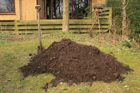 garden compost pile with shovel in residential backyard, organic material for gardening