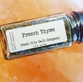 glass jar of french thyme herb from steel city salt company on pink salt background